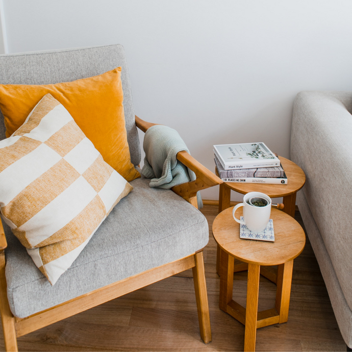 Clean coffee table beside a single couch chair with yellow cushions